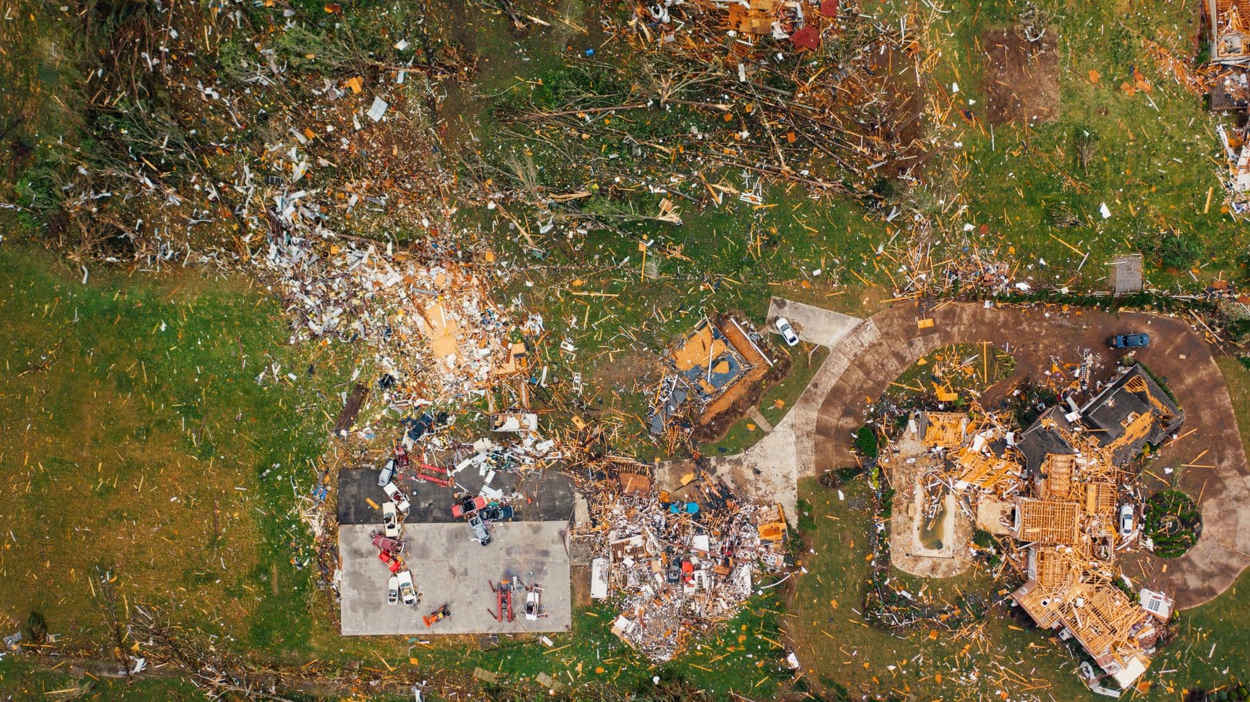 An aerial view of houses torn apart by a storm, with debris scattered across the yards.